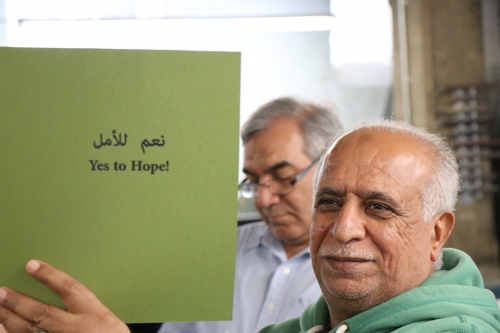 As part of the Friends, Peace, and Sanctuary project (pg. 38), Abdul Karim holds up Yes to Hope, an anthology participants penned about family, food, and home. 